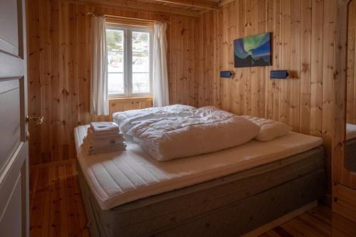 a bedroom with a bed in a wooden room at Explorers Cabin Lofoten Edge in Sørvågen