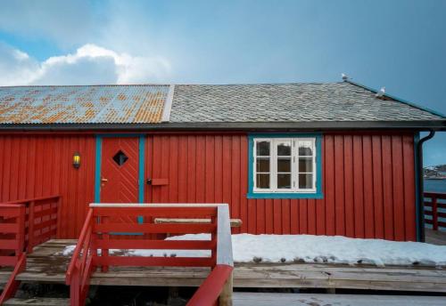 a red building with a window and a red bench at Explorers Cabin Lofoten Edge in Sørvågen