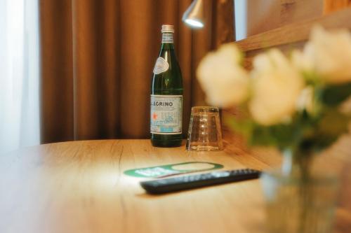 eine Flasche Wein und eine Fernbedienung auf dem Tisch in der Unterkunft Outlet Hotel in Metzingen