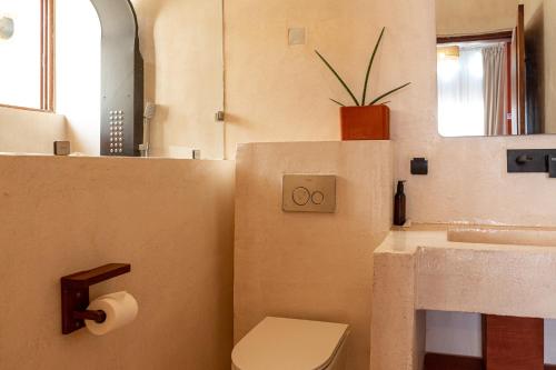 a bathroom with a sink and a toilet and a mirror at Tamarin Hôtel in Cotonou