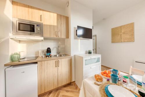 une petite cuisine avec un évier et un micro-ondes dans l'établissement Luxury studio Maisons-Alfort with garden, à Maisons-Alfort