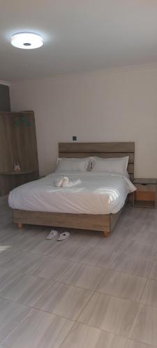 1 dormitorio con 1 cama grande con zapatos en el suelo en Maara Lodge Chogoria, en Igoji