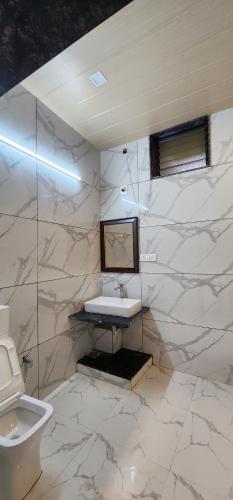 a white bathroom with a sink and a toilet at Palm Valley Farmhouse in Mount Ābu