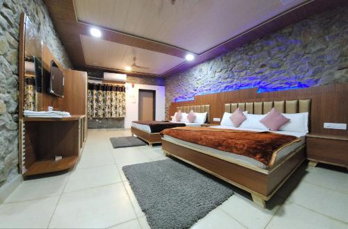 a hotel room with two beds and a tv at Palm Valley Farmhouse in Mount Ābu