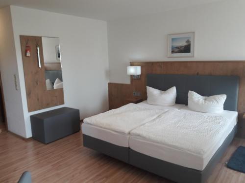 Schlafzimmer mit einem Bett mit weißer Bettwäsche und einem Spiegel in der Unterkunft Gasthof Pension Grüne Au 