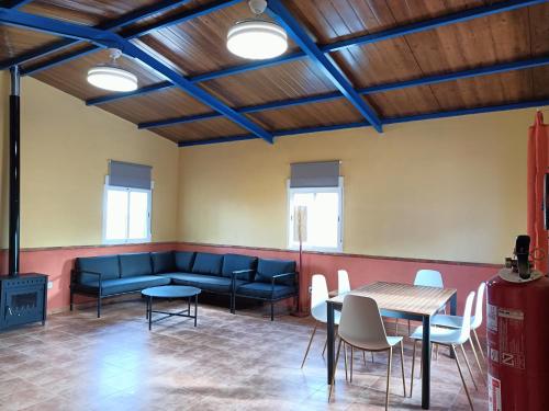 una sala de espera con sofá, mesas y sillas en La Venta de las Estrellas Casas Rurales en Valdepeñas