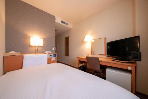 福岡市にある福岡フローラルイン西中洲のベッド、デスク、テレビが備わるホテルルームです。