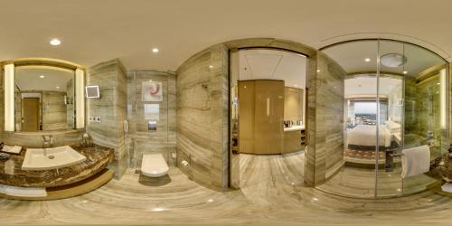 ein Badezimmer mit einem großen Zimmer mit einem Bett und Spiegeln in der Unterkunft Renaissance Lucknow Hotel in Lucknow