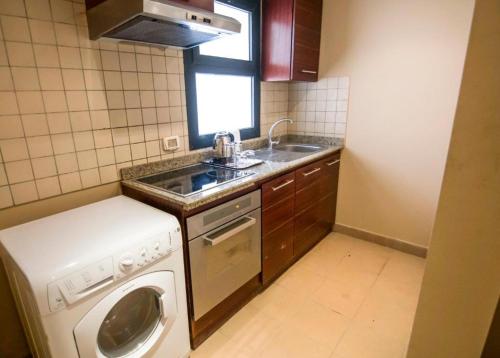 una pequeña cocina con lavadora y fregadero en Port Ghalib Marina Residence Suites, en Port Ghalib