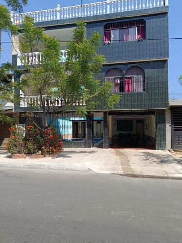un edificio azul con un árbol delante de él en Cambulos House en Melgar