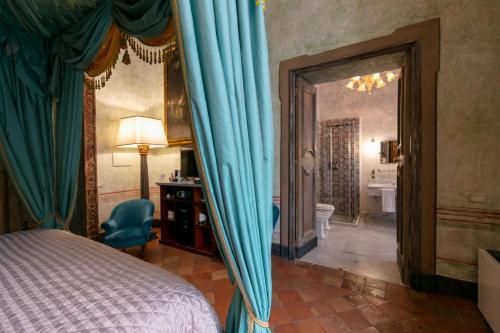 a bedroom with a bed with blue curtains and a bathroom at Palazzo Doria Napoli in Naples