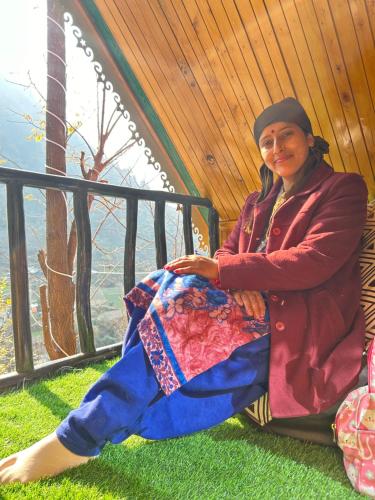 a woman sitting on the grass in a tent at Sainj Riverside Cottages in Sainj