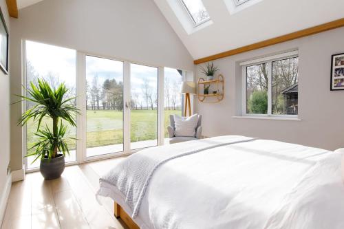 a bedroom with a large bed and large windows at Luxury Cottage Conversion ~ Close to Beaches in Birdham