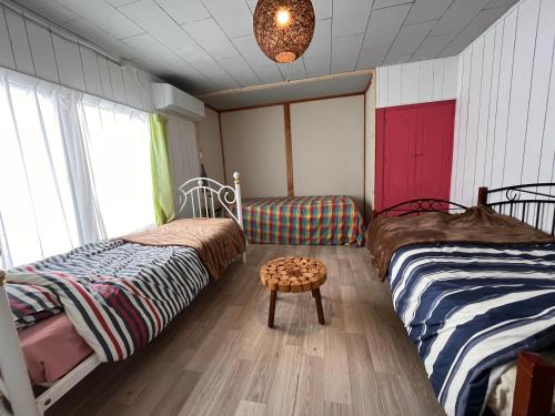 a bedroom with two beds and a table in it at TOTONOU Place in Asahikawa
