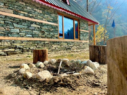 a stone house with a fire pit in front of it at Sainj Riverside Cottages in Sainj
