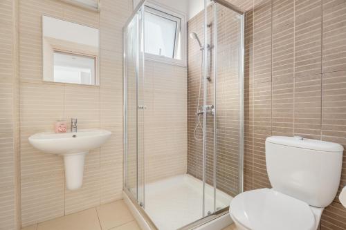 ein Bad mit einer Dusche, einem WC und einem Waschbecken in der Unterkunft Stunning one-bedroom apartment with sea views in Protaras