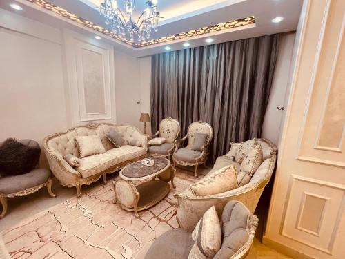 una sala de estar con sofás, sillas y una lámpara de araña. en برج الولاء بالغشام شقة فندقية Vip, en Manshīyat as Sādāt