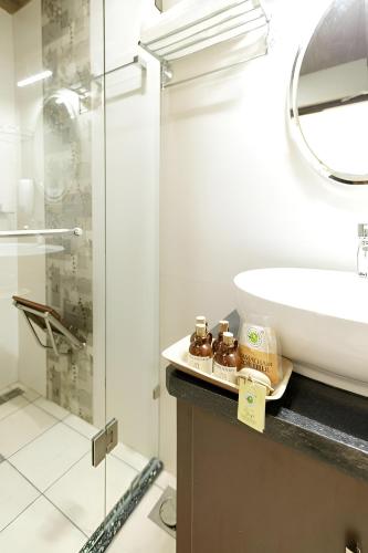 a bathroom with a sink and a glass shower at Lhasa Ayurveda and Wellness Resort - A BluSalzz Collection, Kochi, Kerala in Cochin