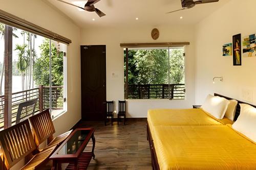 um quarto com uma grande cama amarela e 2 janelas em Lhasa Ayurveda and Wellness Resort - A BluSalzz Collection, Kochi, Kerala em Cochin