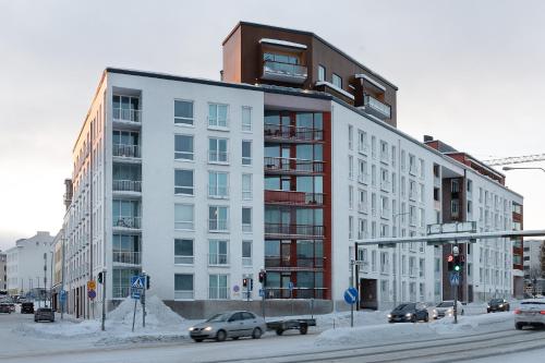 a large white building on a city street with cars at Holiday Apartment Aava 4 in Rovaniemi