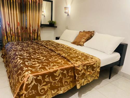 um quarto com uma cama grande com lençóis brancos e dourados em Sea Shine Guest House em Hikkaduwa