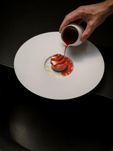 a person holding a plate with a cup of coffee and a pastry at Château de Vignée in Rochefort