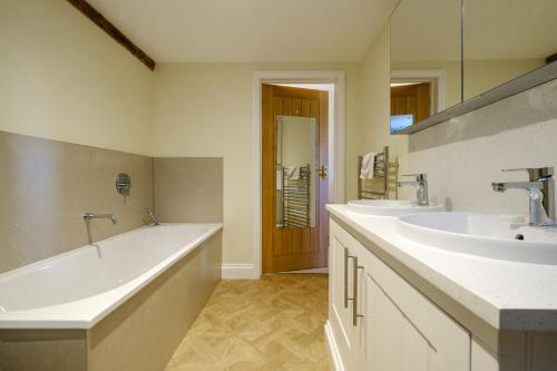 a bathroom with two sinks and a bath tub at Upper Barn in Ufford