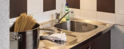 a kitchen counter with a sink and a pot of utensils at Appartéa Grenoble Alpexpo in Grenoble