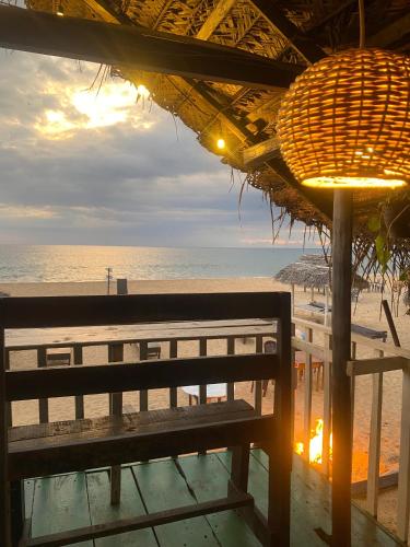 a bench on the beach with the ocean in the background at Sea Shine Guest House in Hikkaduwa