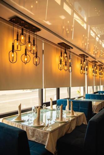 a dining room with two tables and chandeliers at Hotel Zhibek Zholy in Shymkent
