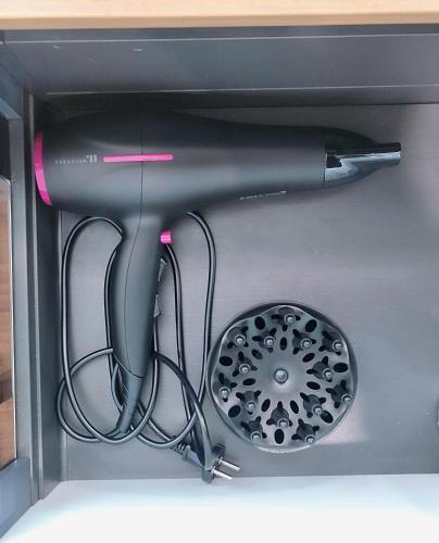 un sèche-cheveux noir et une brosse dans un tiroir dans l'établissement Auberwood - Cozy apartment near Paris !, à Aubervilliers