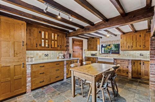 eine Küche mit Holzschränken und einem Holztisch in der Unterkunft Rustic 5 Bed Farm House in Derbyshire, sleeps 9 