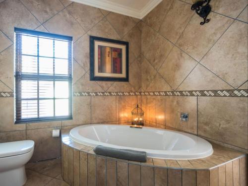 a bathroom with a tub and a toilet and a window at Isiphiwo Village Accommodation Venue and Spa in Pretoria