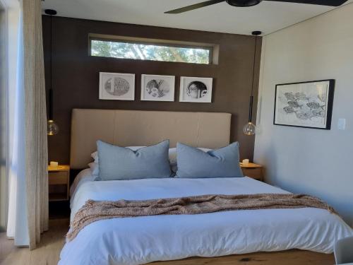 a bedroom with a bed with blue pillows and a window at Quaint Cottage in Hermanus