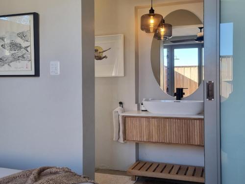 a bathroom with a sink and a mirror at Quaint Cottage in Hermanus