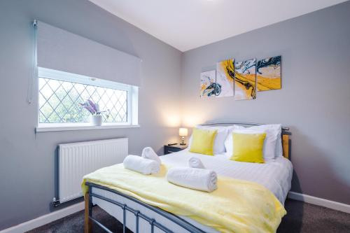 ein Schlafzimmer mit einem Bett mit gelben Kissen und einem Fenster in der Unterkunft Poplar House- Contractor Friendly 3 Bedroom Bright Modern House with a Sofa Bed in Preston