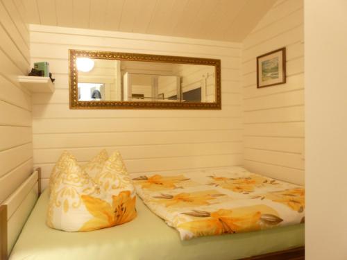 a bedroom with a bed with a mirror and pillows at Ferienhaus direkt am See - a56012 in Dabel