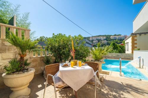 una mesa y sillas en un patio junto a la piscina en Apartments Villa Aura en Dubrovnik