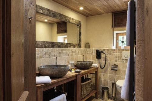 a bathroom with two sinks and a mirror at Le Logis des Prés Verts Villa avec Jacuzzi Privatif in Jouey
