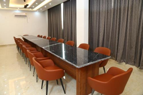 uma sala de conferências com uma mesa longa e cadeiras laranja em MK Regency em Greater Noida