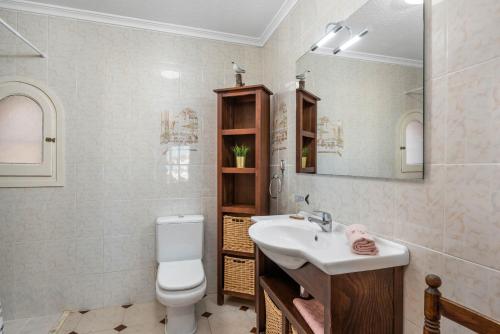een badkamer met een wastafel, een toilet en een spiegel bij Villa Aloe - PlusHolidays in Calpe