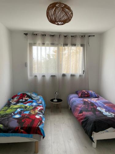 two twin beds in a room with a window at Maison Bijou 3 chambres à 10min de DisneyLand Paris in Chalifert