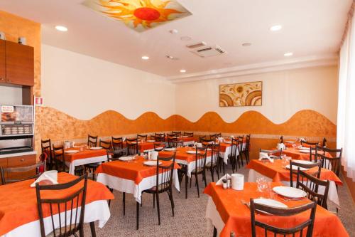 a restaurant with orange tables and chairs in a room at Hotel Sandra in Gatteo a Mare