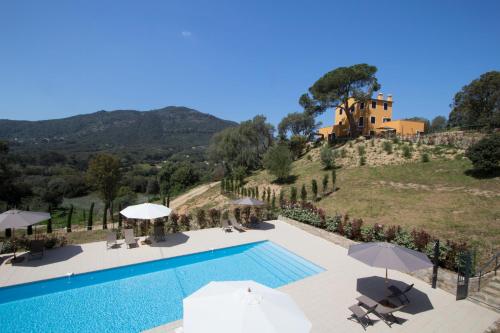 une piscine avec parasols et une maison sur une colline dans l'établissement Le Domaine Saint François La Tour 3, à Ajaccio