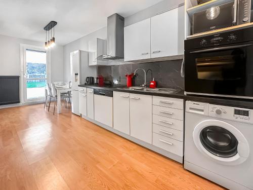 een keuken met witte kasten en een wasmachine en droger bij La Belle Époque d'Annecy in Annecy