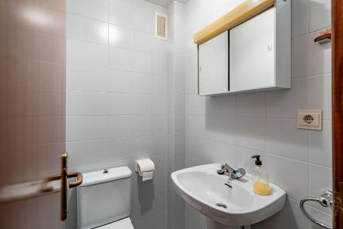 a white bathroom with a sink and a toilet at Piso con Piscina in Santander