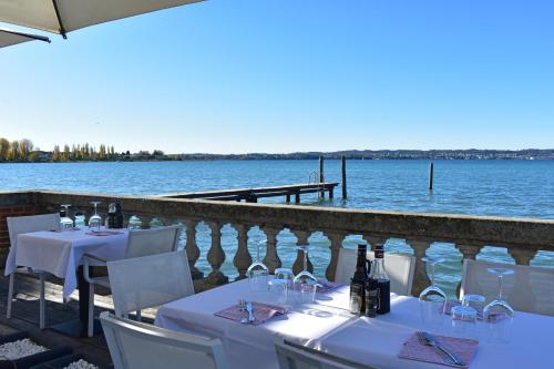 a table with wine bottles and chairs next to the water at Villa Pioppi Hotel in Sirmione