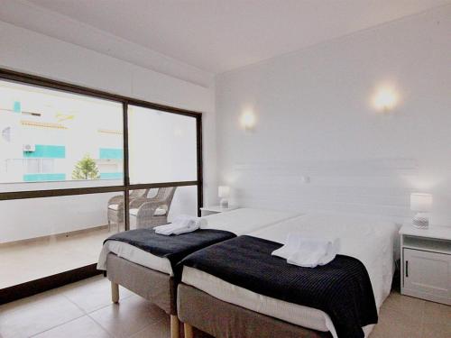 ヴィラモウラにあるAmendoeiras I - Central Vilamouraの白いベッドルーム(ベッド1台、大きな窓付)