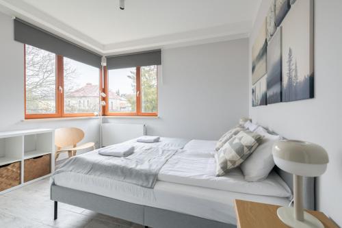 a white bedroom with a bed and a desk at Dom & House - Apartments Sopot Kamienny Potok in Sopot