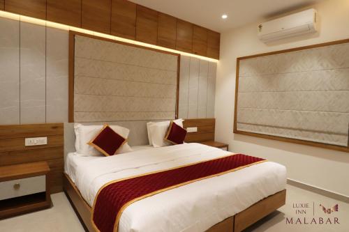 a bedroom with a large bed and a large screen at LUXIE INN MALABAR in Perintalmanna